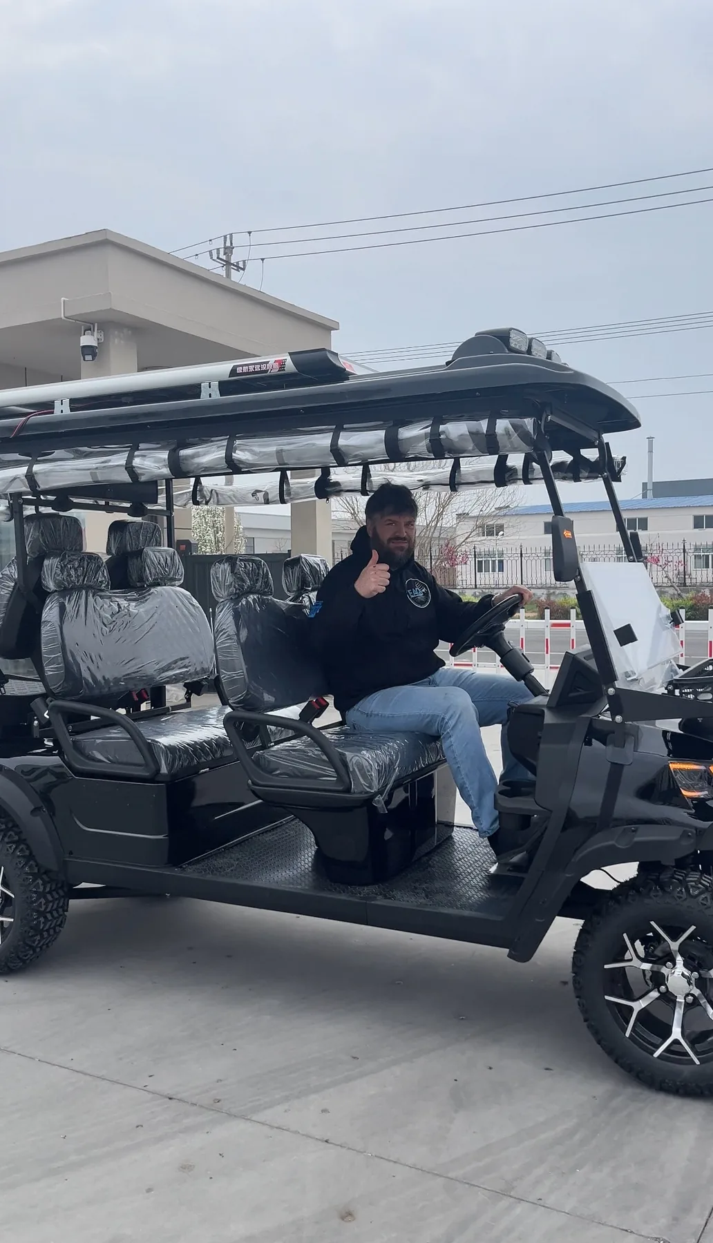 A person seated at the steering wheel of a golf cart outside a building