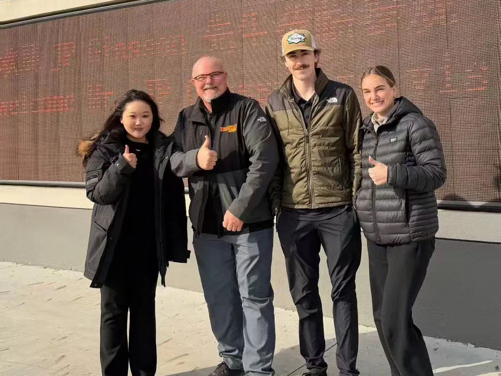 Four people standing together outdoors in front of a building